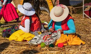 Two Uro women embroiders their handicrafts on floating island in Lake Titicaca near Puno, Peru